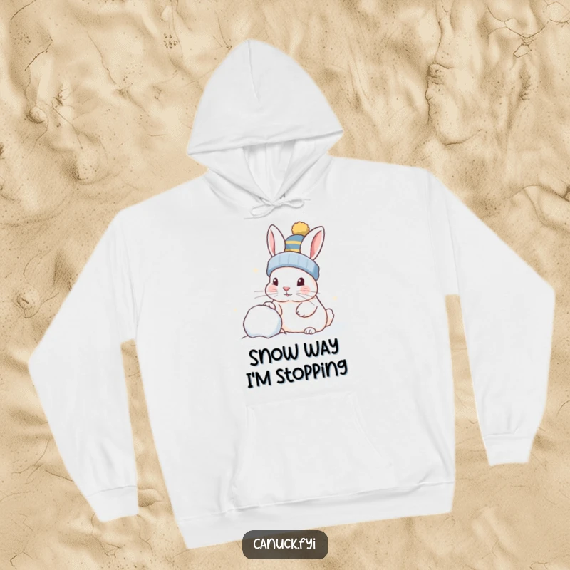 Funny rabbit in a toque, playfully nudging a snowball, cozy hoodie, perfect for winter fans.